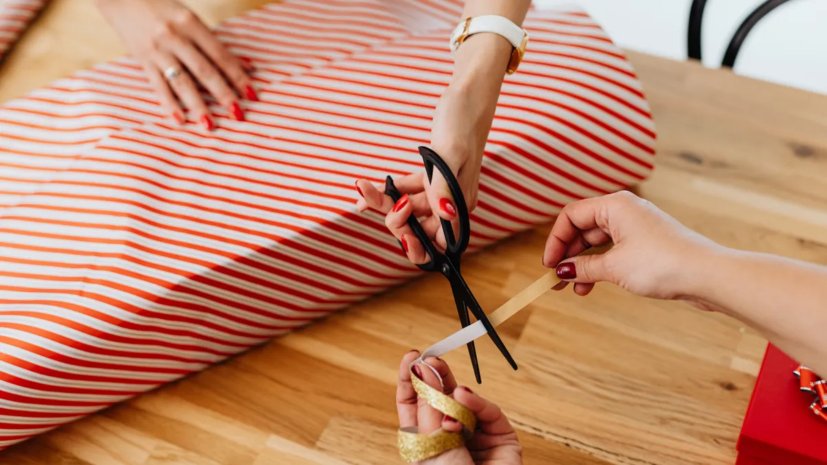 Hands cutting striped wrapping paper on a large gift