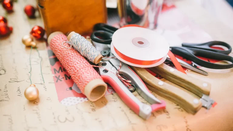 Gift wrapping supplies with scissors, tape, ribbon, and paper rolls