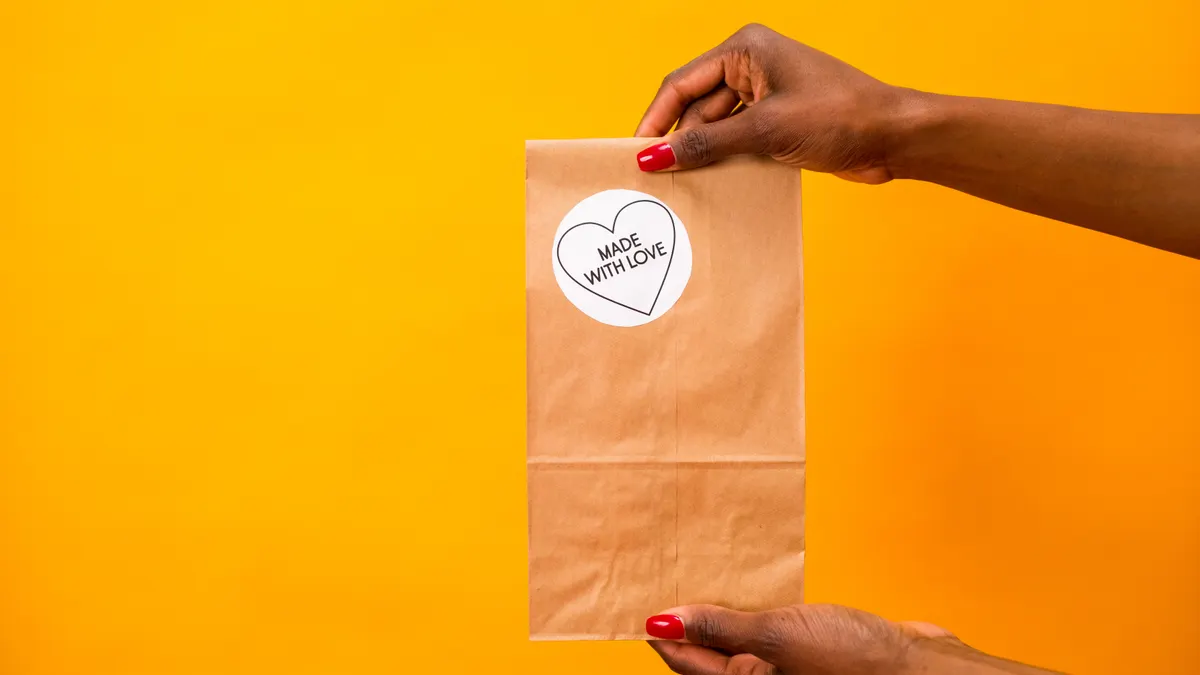 hands holding a plain brown paper gift bag