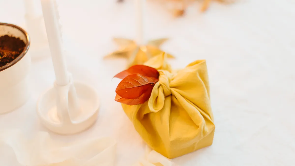 Yellow gift wrapped in fabric with a leaf accent