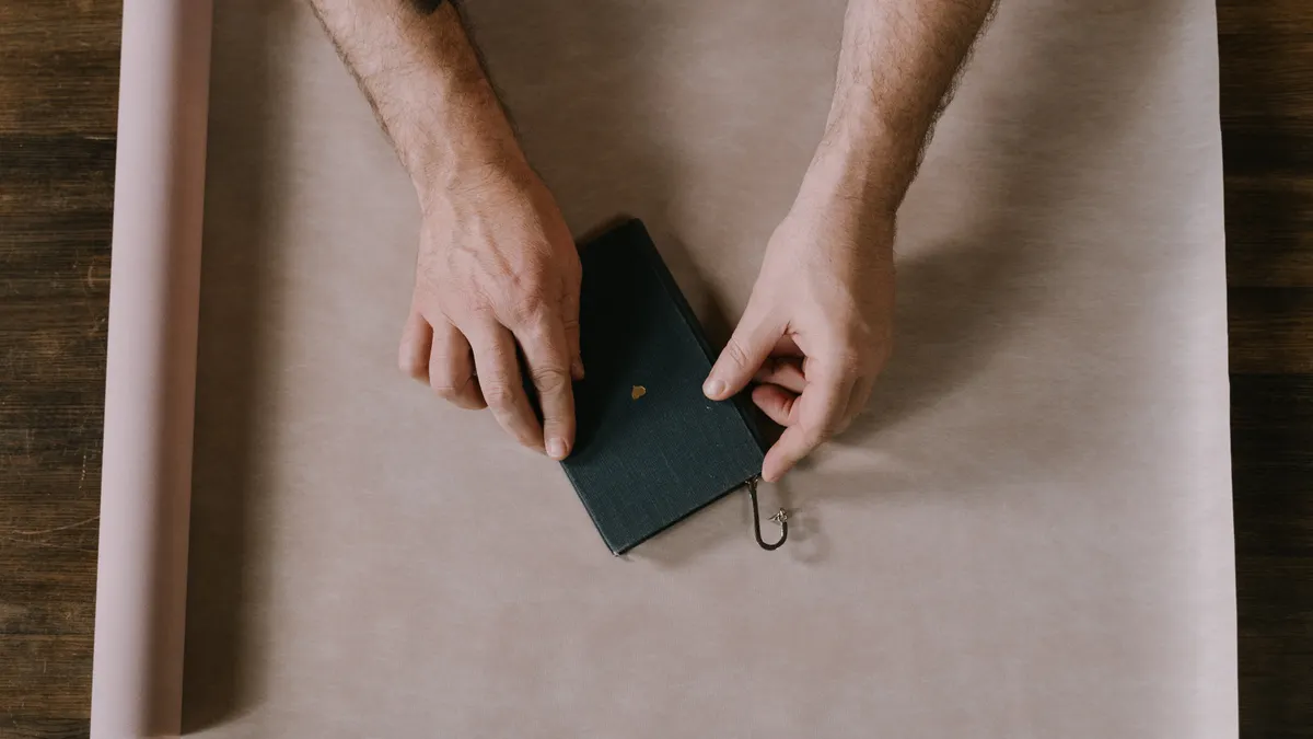 Hands wrapping a small box with brown paper