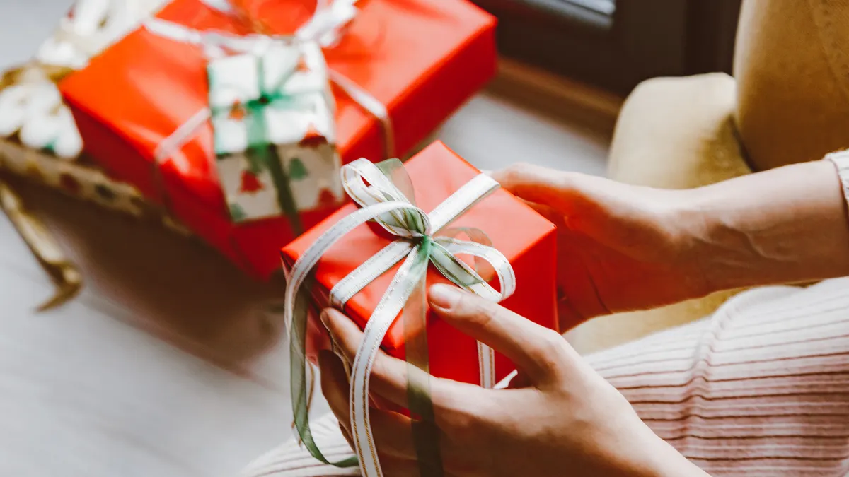 Hands adjusting ribbon on wrapped presents