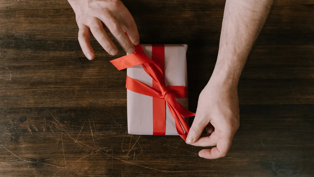 How to wrap a present without tape hands tying ribbon on a small gift box