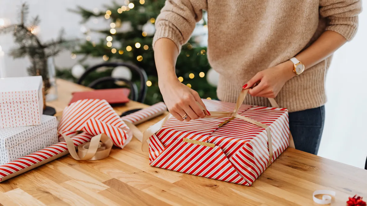 person wrapping a rectangular present on a table